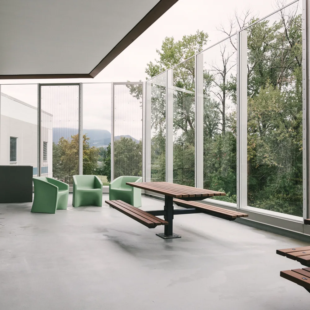 Glazed dining area with timber picnic tables looking into woodland