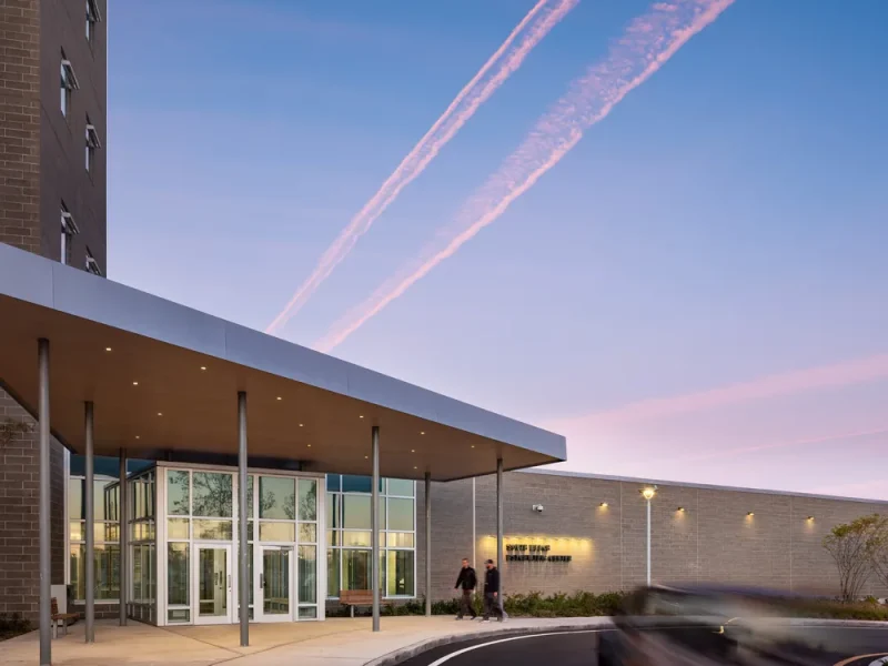 Entrance canopy of the inpatient building photographed at dusk beneath a pink sky